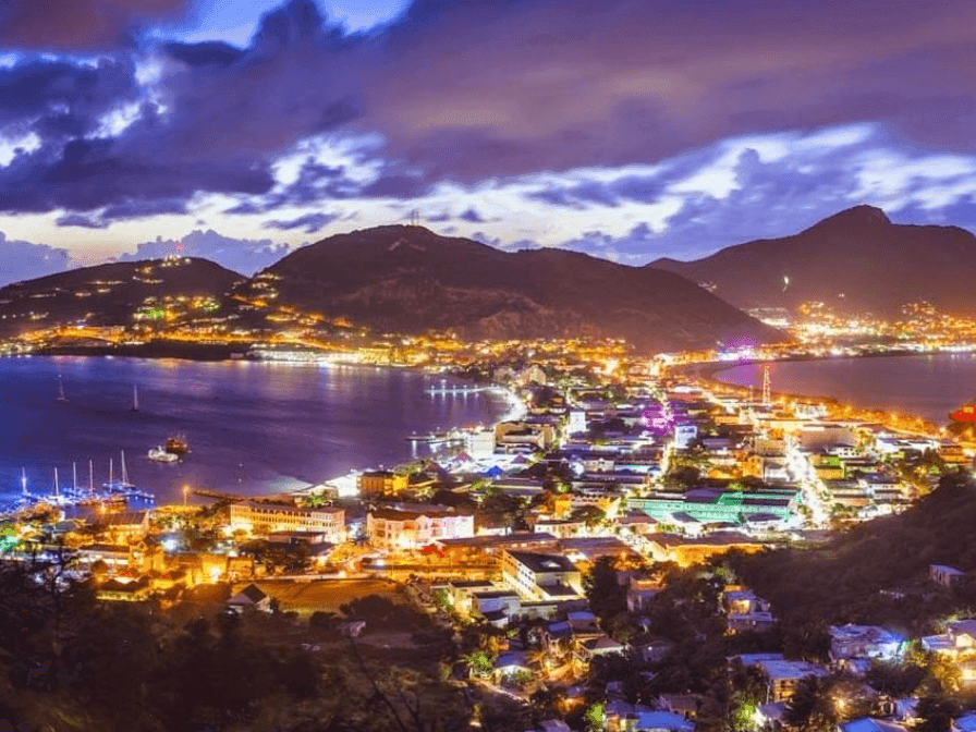 Nighttime aerial view of the cityscape and mountains surrounding the brightly lit bay near The Morgan Resort Spa Village